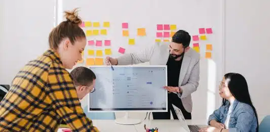 man standing behind flat screen computer monitor